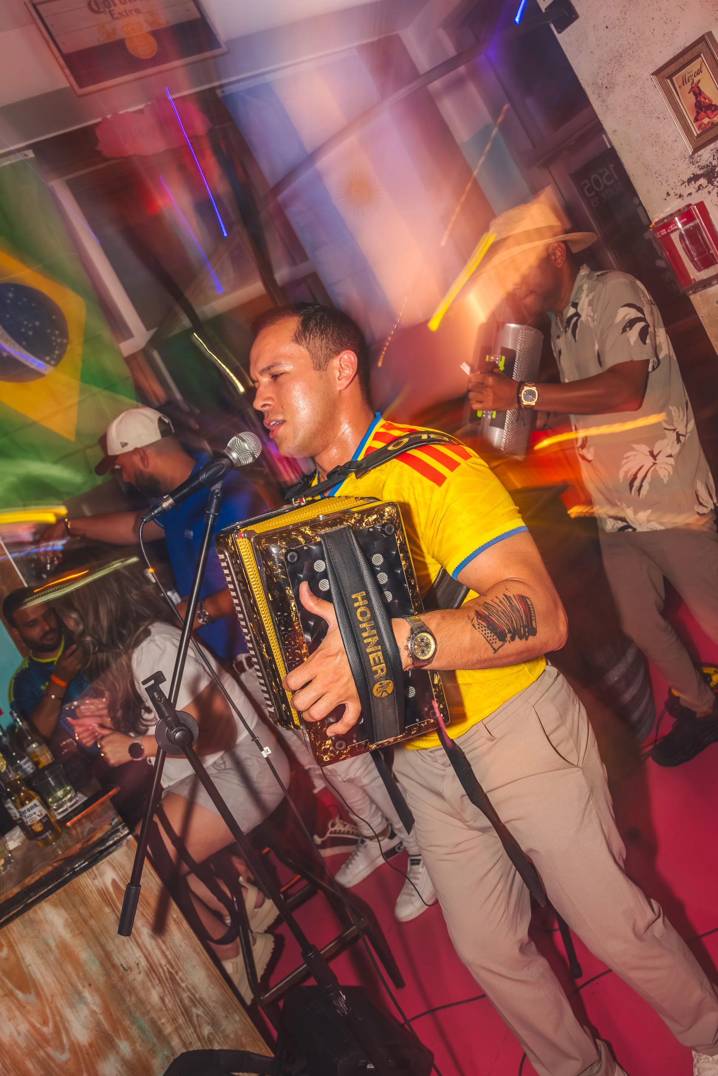 Acordeonista interpretando música entre asistentes con camisetas de Colombia.