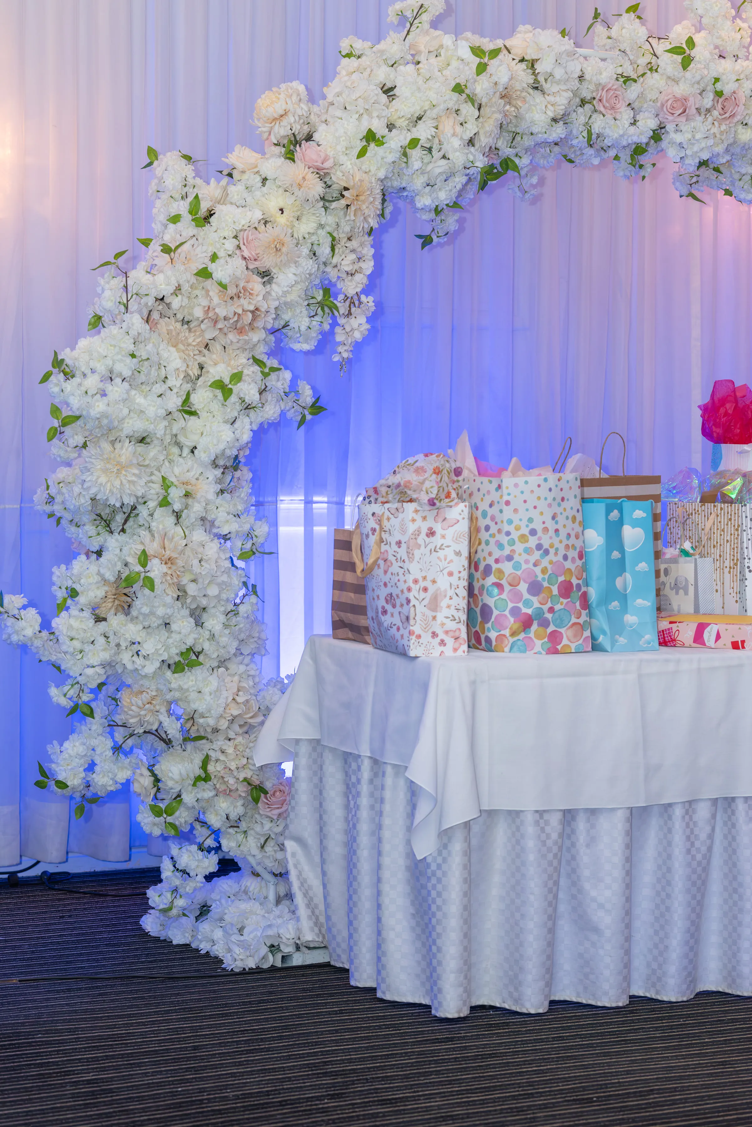 Regalos dispuestos junto a la decoración floral del baby shower.