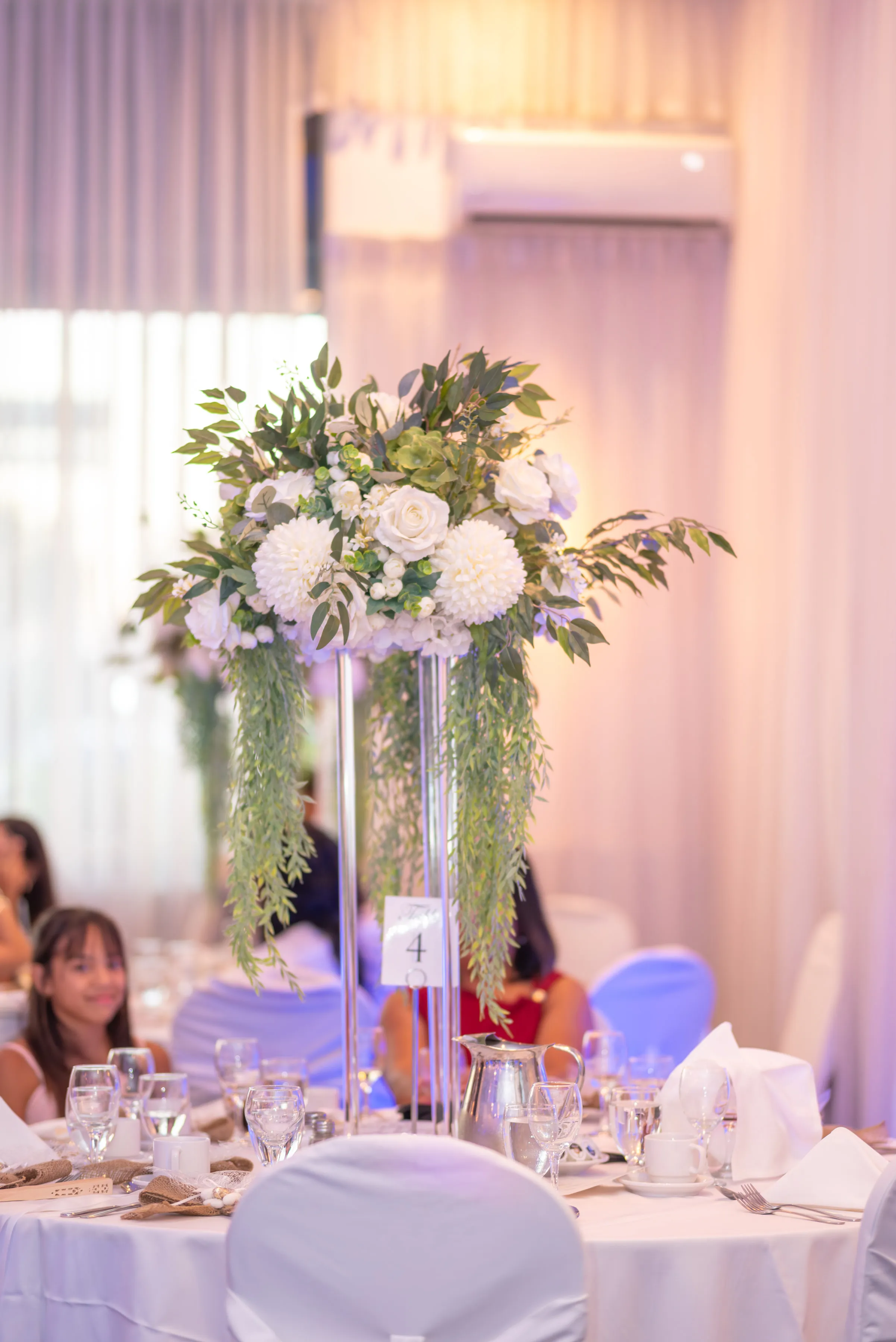 Arreglo alto de flores blancas y follaje en el baby shower.