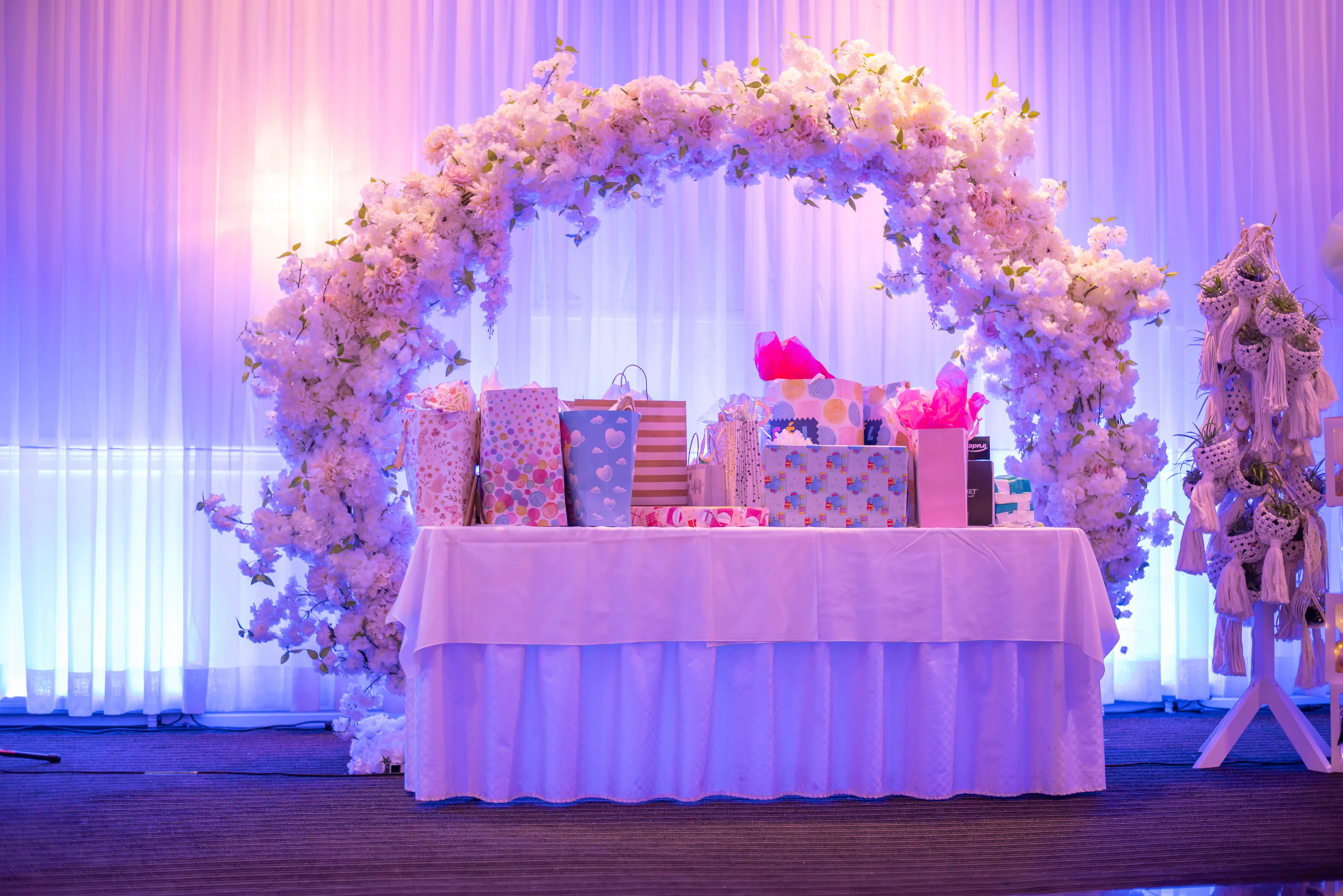 Mesa de regalos enmarcada por un arco floral durante el baby shower.