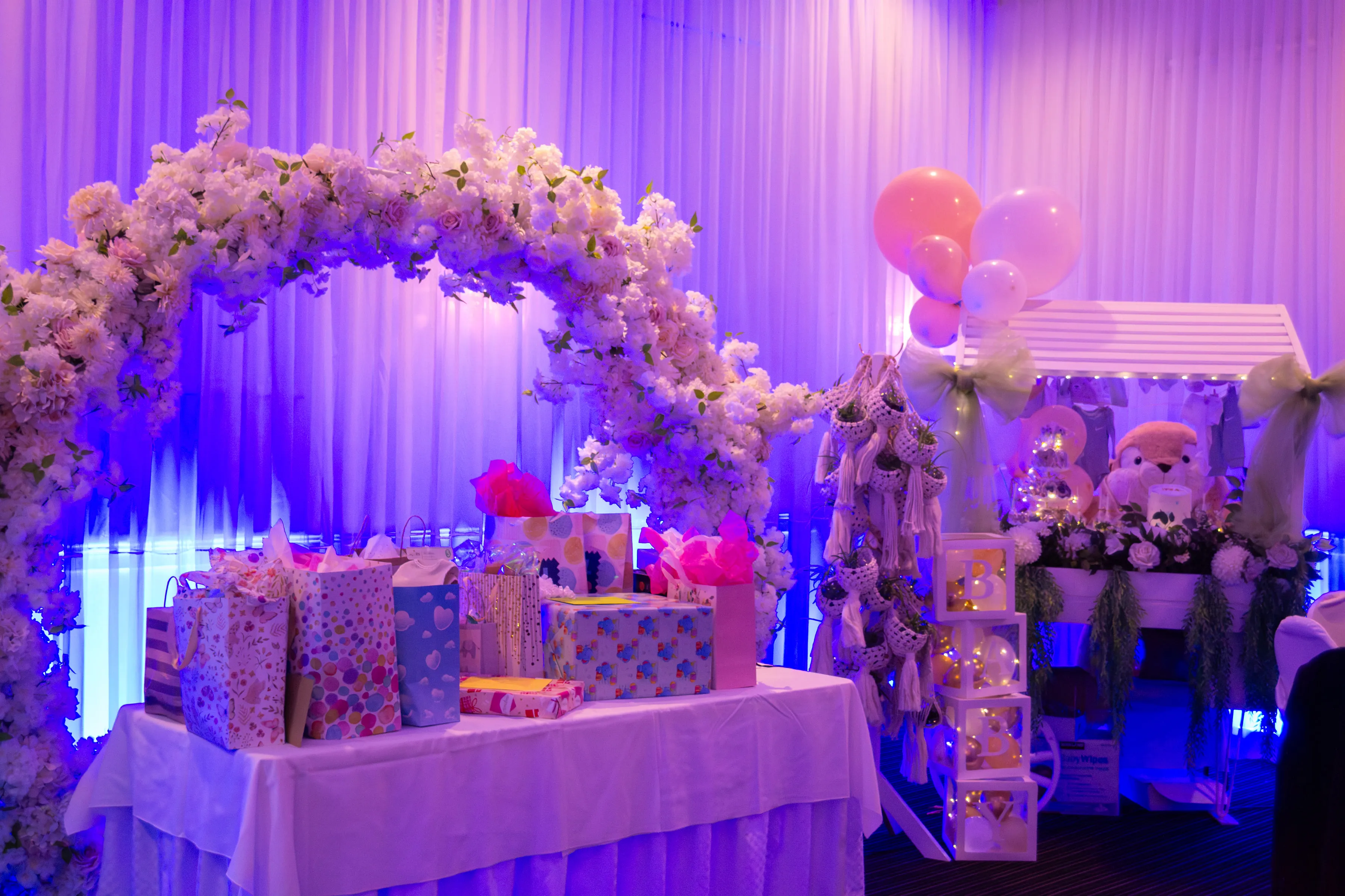 Vista amplia de la mesa de regalos y el arco floral del baby shower.