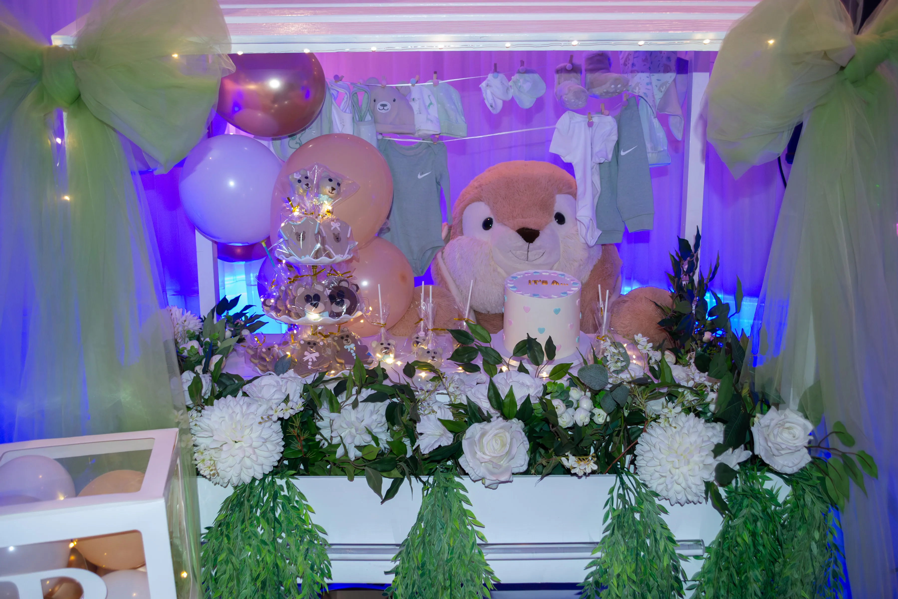 Mesa principal decorada con flores, globos y un oso de peluche.