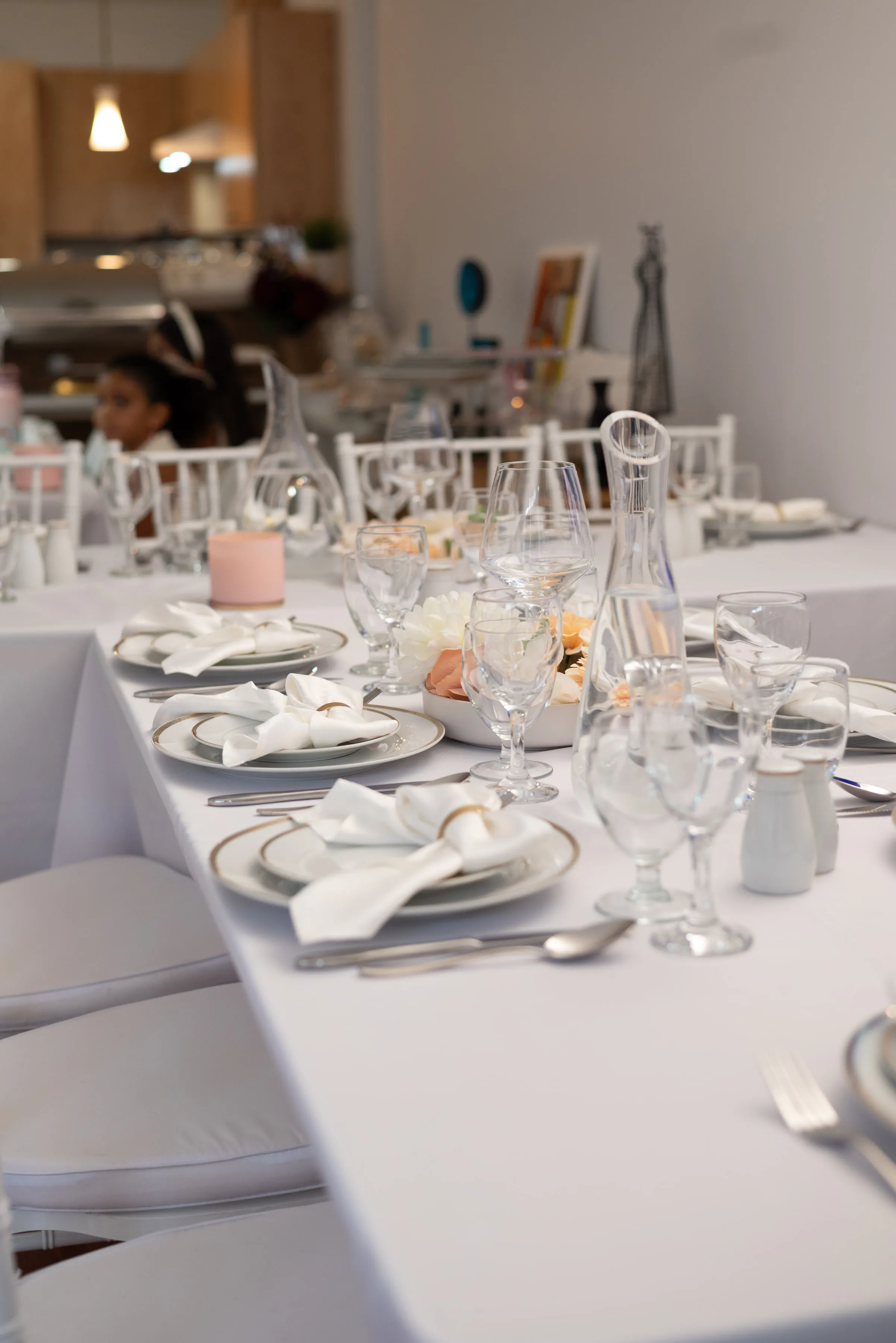 Mesa de invitados preparada con vajilla blanca y cristalería.